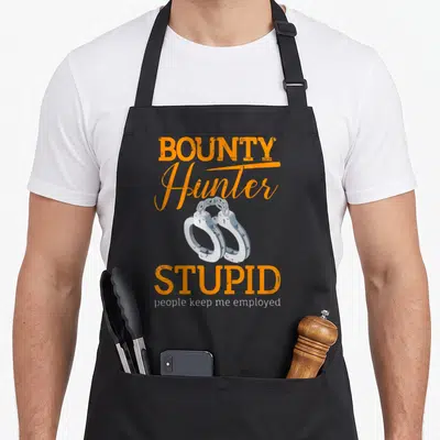 Bounty stupid aprons - Orange and white text with silver handcuffs graphic reading bounty hunter stupid people keep me — shown on a black cotton canvas apron against a white background
