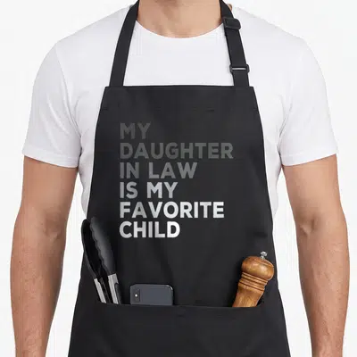 Vintage daughter father day apron - Stacked white and grey text reading My Daughter In Law Is My Favorite Child — shown on a black cotton canvas apron against a white background