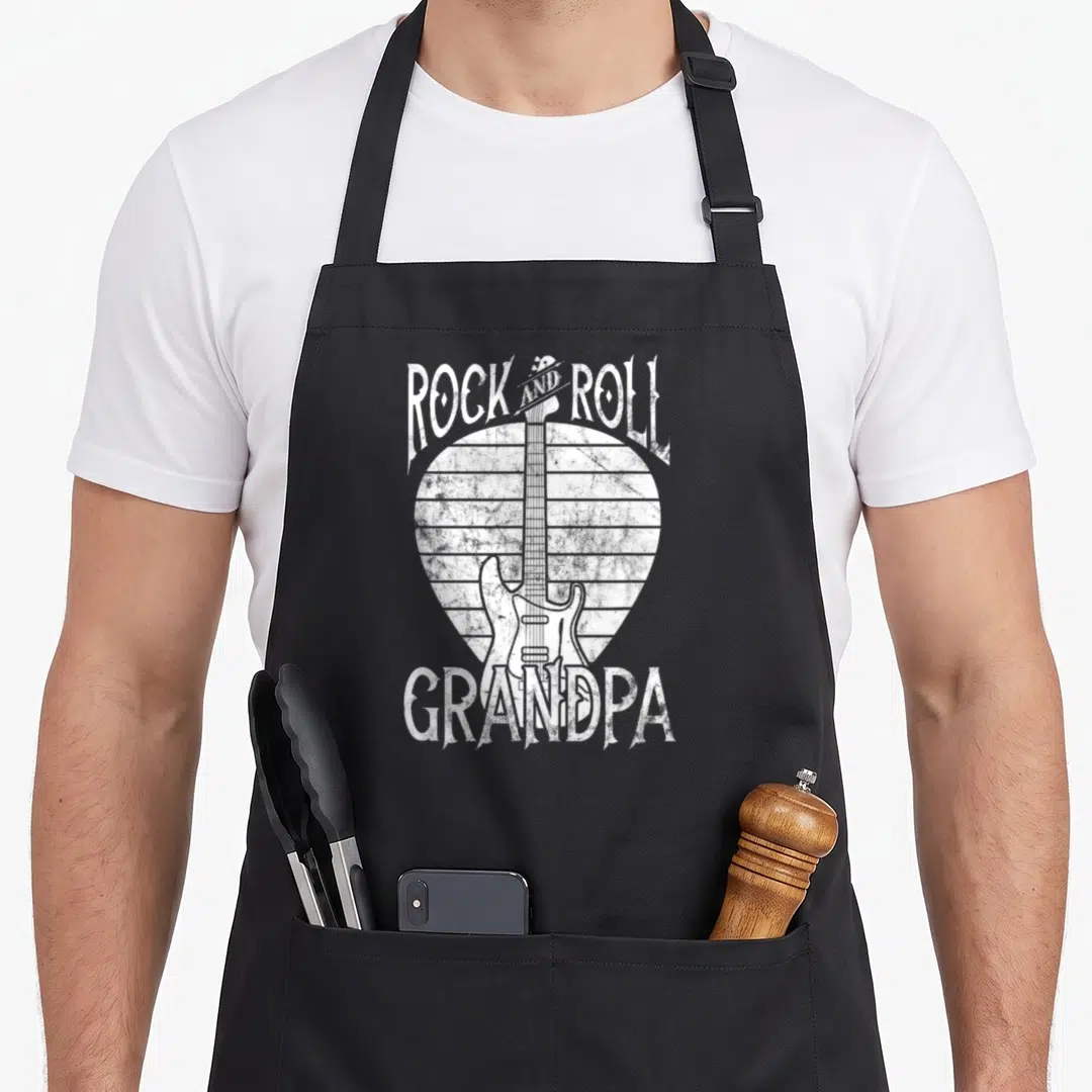 Roll grandpa apron - White distressed electric guitar over striped pick shape with Rock and Roll Grandpa text — shown on a black cotton canvas apron against a white background