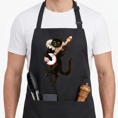 Banjo cat apron - Standing black cat with white ruffle collar playing a banjo in vintage cartoon style — shown on a black cotton canvas apron against a white background