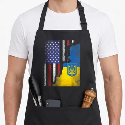 Ukrainian ukraine american flag apron - Distressed US and Ukraine flags merging with a map silhouette and yellow — shown on a black cotton canvas apron against a white background