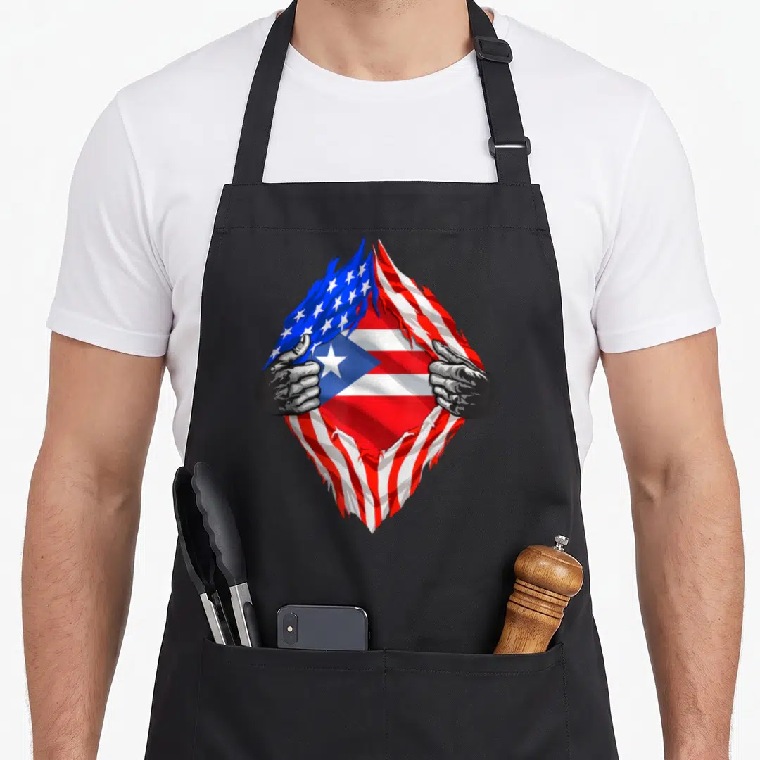 Rico patriotic apron - Two grey hands tear a flag to reveal red white blue Puerto Rican flag — shown on a black cotton canvas apron against a white background
