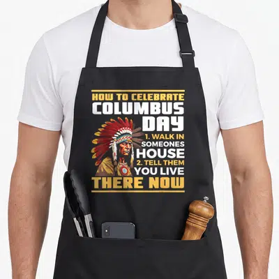 Funny aboriginal native american apron - Cartoon Native American man with text How To Celebrate Columbus Day — shown on a black cotton canvas apron against a white background