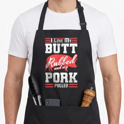 Pulled i love my pig apron - Red pig silhouette with stacked white text reading I Love My Butt Rubbed Pork Pulled — shown on a black cotton canvas apron against a white background