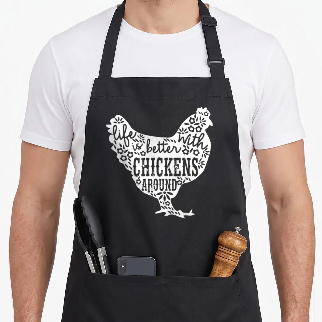 Better farmers apron - White chicken silhouette formed by text life is better with chickens around and small flowers — shown on a black cotton canvas apron against a white background