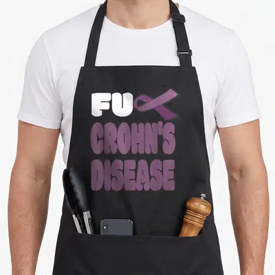 Crohn disease awareness ribbon apron - Stacked text FU CROHN'S DISEASE with purple ribbon replacing CK letter — shown on a black cotton canvas apron against a white background
