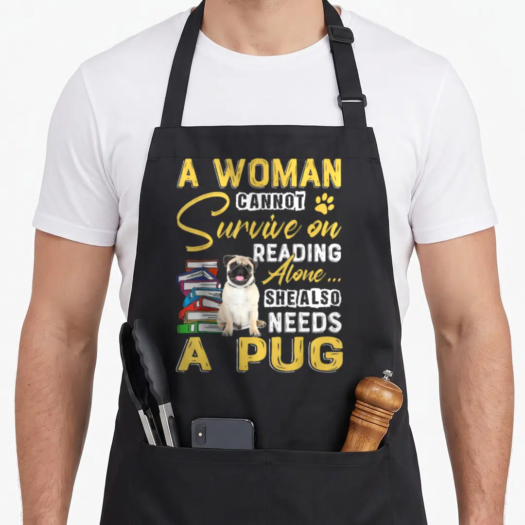 Bookaholic dog apron - Cartoon pug sitting by books with yellow and white stacked text — shown on a black cotton canvas apron against a white background