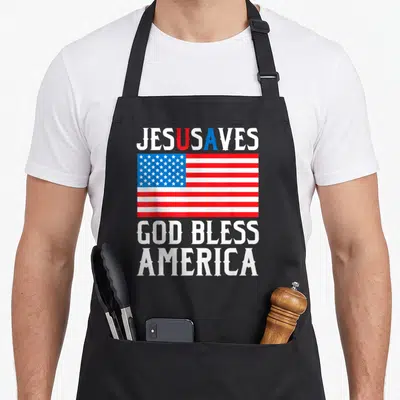 Christ class funny apron - USA flag centered between JESUS SAVES and GOD BLESS AMERICA text in red white and blue — shown on a black cotton canvas apron against a white background