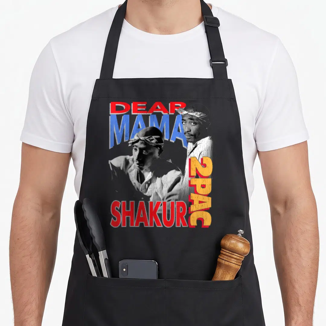 Dear mama apron - Tupac portraits with distressed red blue orange DEAR MAMA SHAKUR 2PAC text on grey background — shown on a black cotton canvas apron against a white background