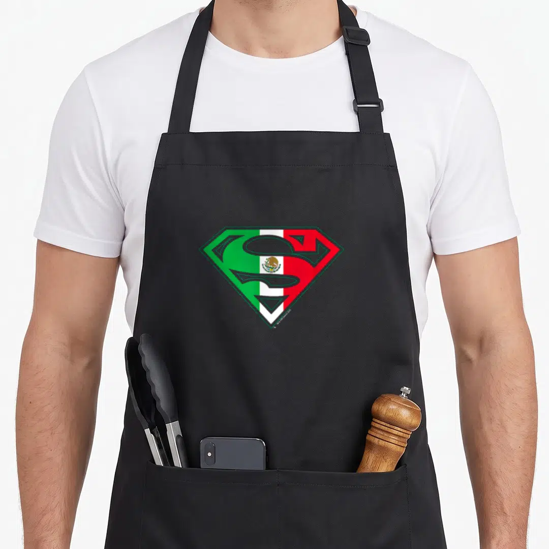 Shield mexican apron - Superman S shield filled with green white red Mexican flag colors and eagle emblem — shown on a black cotton canvas apron against a white background