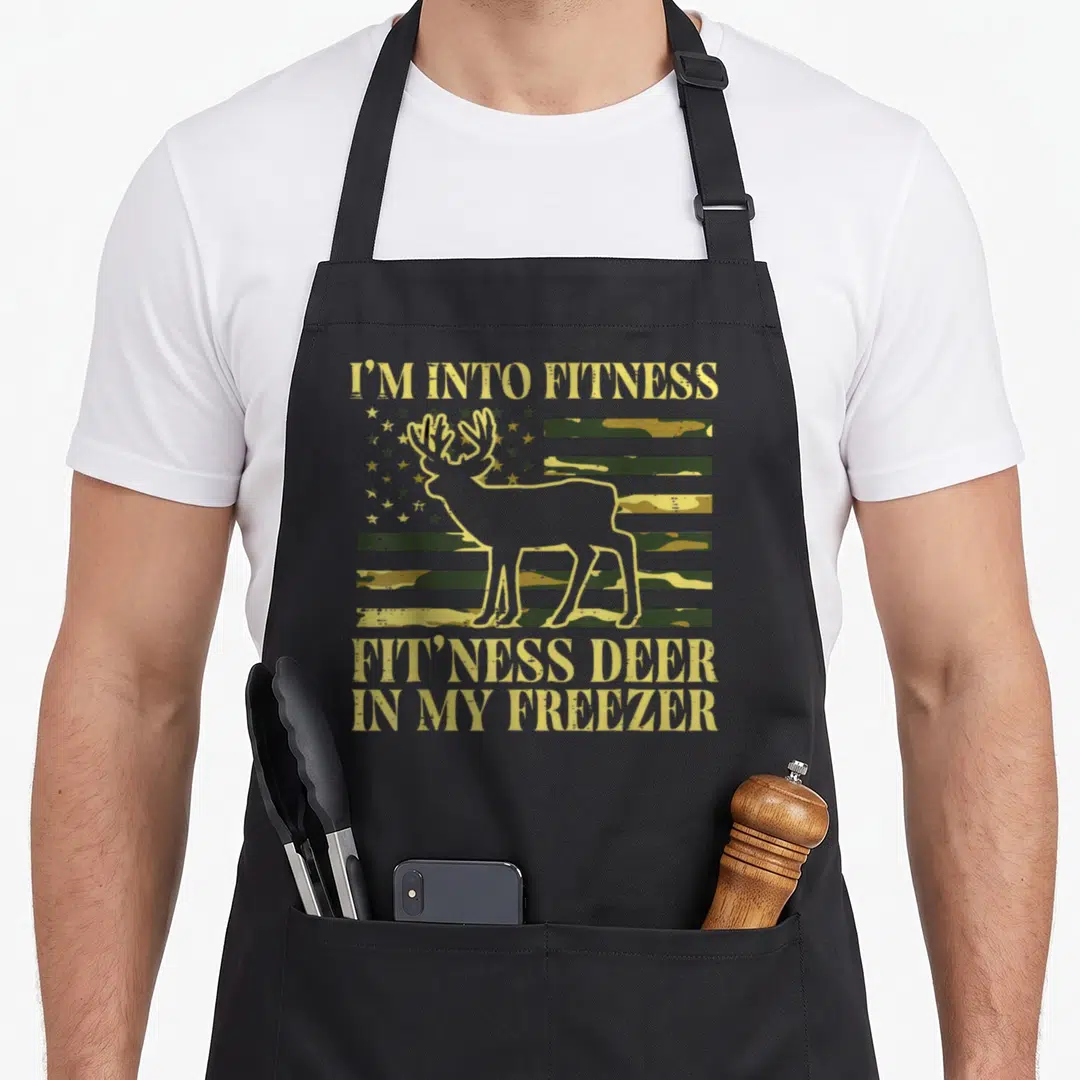 Fitness farmer hunting apron - Deer outline over camo flag with gold text reading I'm into fitness fit ness deer in my — shown on a black cotton canvas apron against a white background