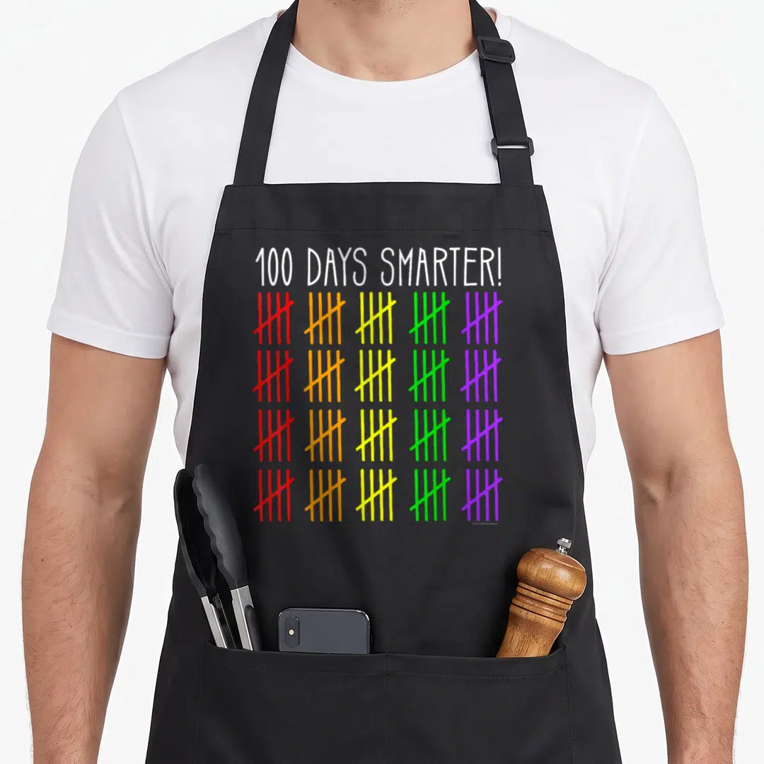 Smarter counting teacher apron - 100 DAYS SMARTER text above four rows of five colorful tally mark groups in red orange — shown on a black cotton canvas apron against a white background