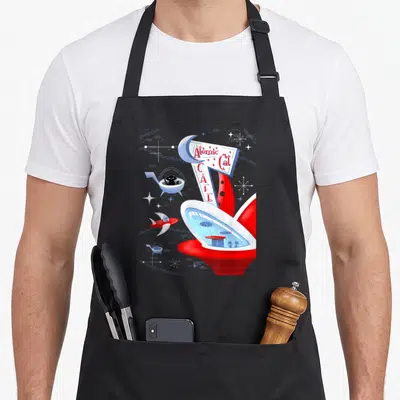 Atomic cat apron - Retro atomic cat cafe sign with black cat in spaceship and rocket in red white blue — shown on a black cotton canvas apron against a white background