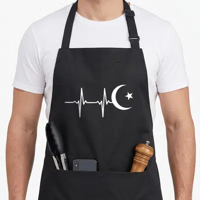 Muslim ramadan apron - White heartbeat line merging into crescent moon and star graphic — shown on a black cotton canvas apron against a white background