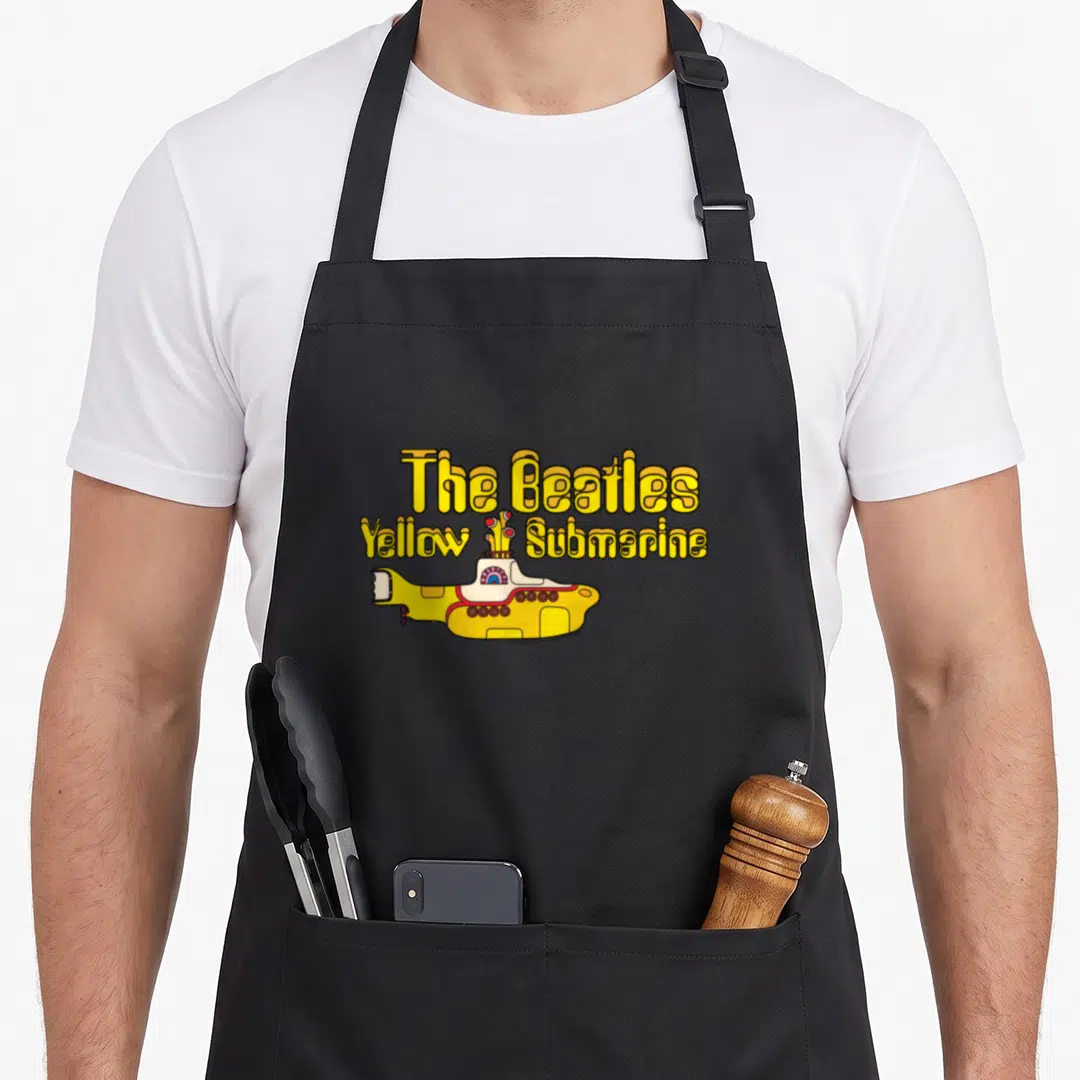Yellow submarine apron for mom - The Beatles Yellow Submarine cartoon text with flowers and yellow submarine — shown on a black cotton canvas apron against a white background