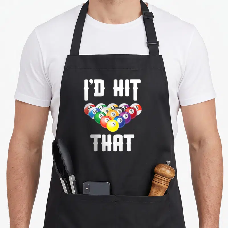 Hit billiards apron - I'd Hit That text surrounding a heart of colorful billiard balls — shown on a black cotton canvas apron against a white background