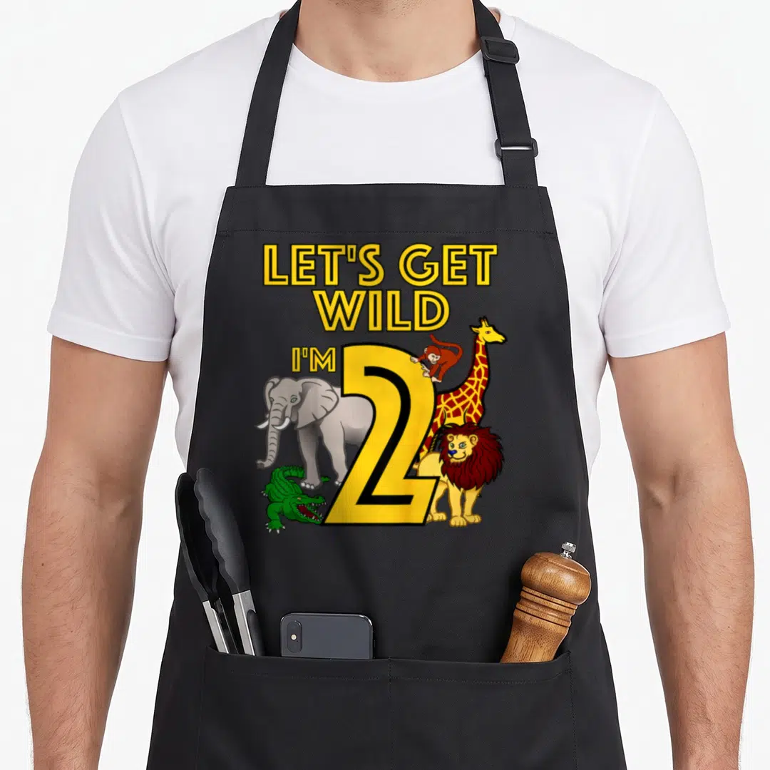 Safari 2nd apron - Cartoon number 2 surrounded by elephant, giraffe, lion, monkey, and crocodile with yellow text — shown on a black cotton canvas apron against a white background