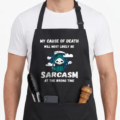 Sarcasm joke apron - Cartoon grim reaper in teal holding scythe with white text about sarcasm cause of death — shown on a black cotton canvas apron against a white background