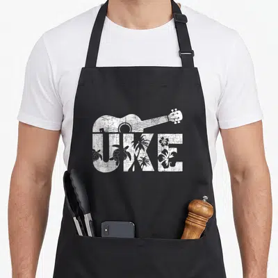Ukulelist ukulele apron - White distressed UKE text with ukulele and tropical turtles palms hibiscus inside letters — shown on a black cotton canvas apron against a white background