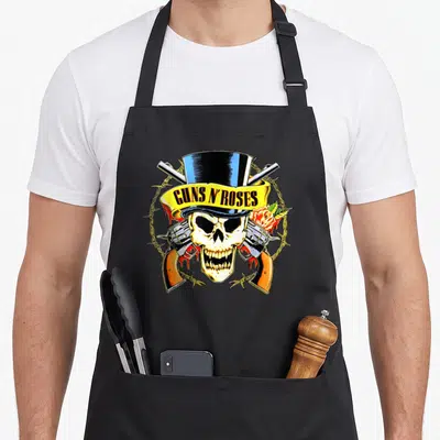 Rose hat gun apron - Skull in blue top hat with crossed guns, yellow ribbon text, barbed wire circle, and rose on right — shown on a black cotton canvas apron against a white background