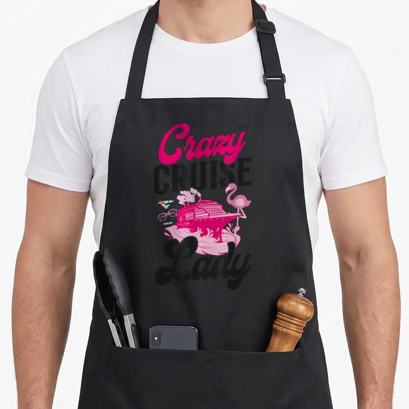 Vacation crazy cruise apron - Pink cruise ship, flamingo, cocktail, and Crazy Cruise Lady text in cartoon art — shown on a black cotton canvas apron against a white background