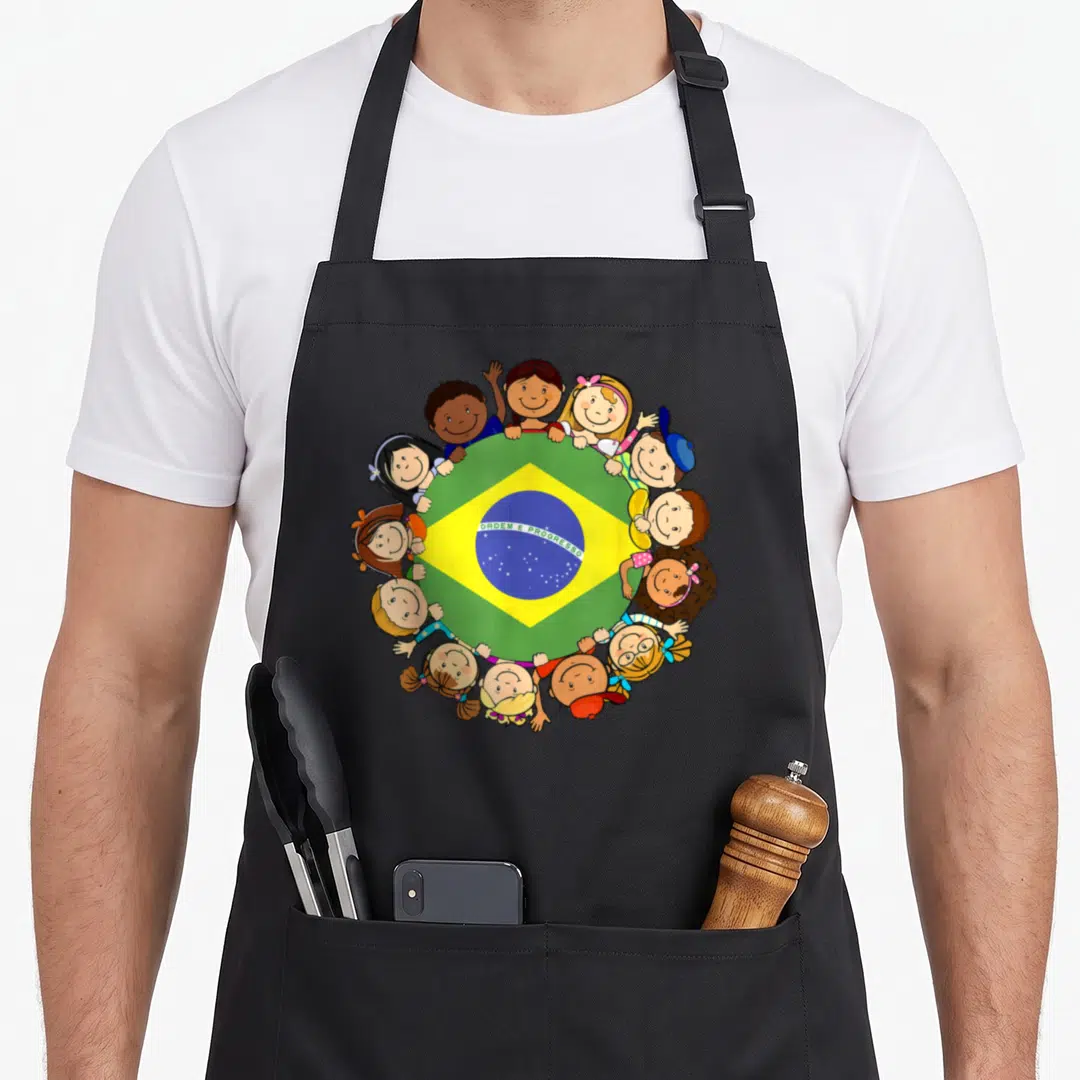 Brazil hispanic aprons - Cartoon children surrounding a circular Brazil flag with green yellow blue colors and text — shown on a black cotton canvas apron against a white background