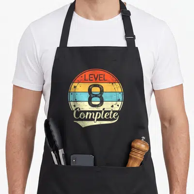 8th anniversary wedding aprons - Retro striped circle with LEVEL 8 Complete text in red yellow blue beige grey — shown on a black cotton canvas apron against a white background