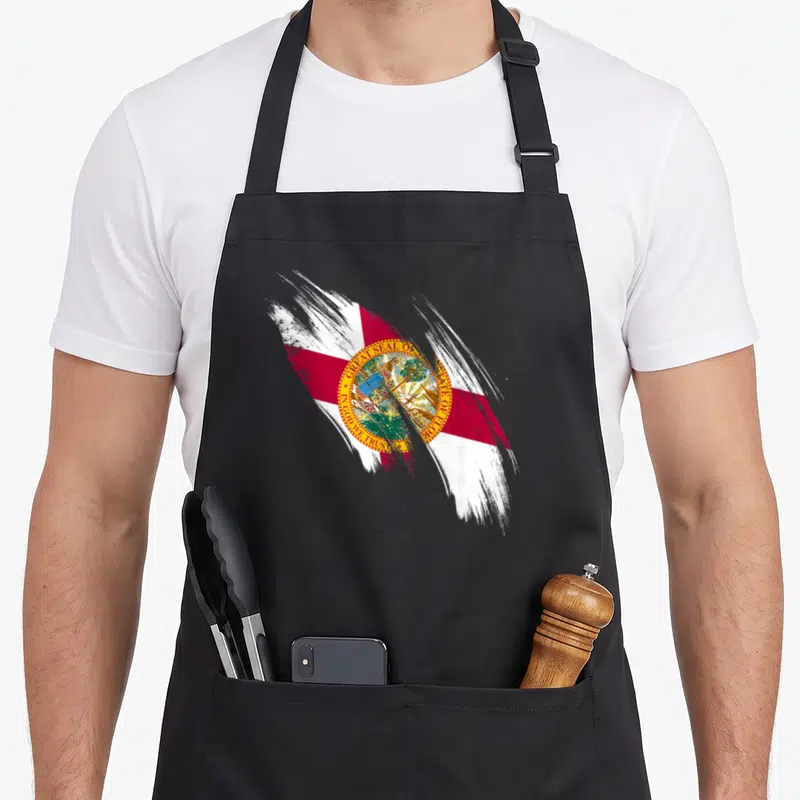 Flag floridian pride apron - Painted Florida flag with red and white brushstrokes and Great Seal text — shown on a black cotton canvas apron against a white background