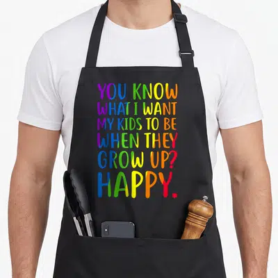 Awareness gay pride apron - Stacked rainbow text reading YOU KNOW WHAT I WANT MY KIDS TO BE WHEN THEY GROW UP? HAPPY — shown on a black cotton canvas apron against a white background