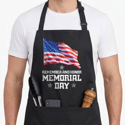 Flag memorial apron - Waving distressed American flag above white text reading Remember and Honor Memorial Day flanked — shown on a black cotton canvas apron against a white background