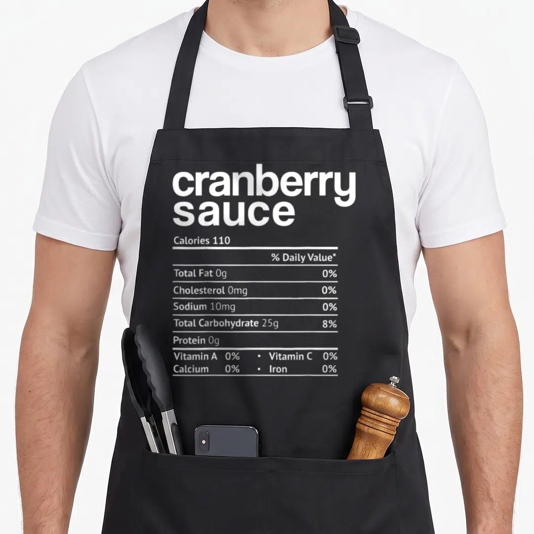 Cranberry christmas apron - White nutrition facts text listing cranberry sauce calories and zero fat values — shown on a black cotton canvas apron against a white background