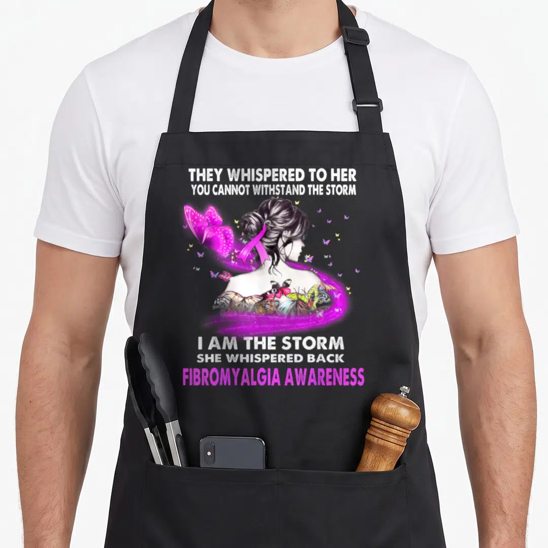 Storm fibromyalgia awareness apron - Woman profile with pink ribbon and butterflies surrounded by Fibromyalgia — shown on a black cotton canvas apron against a white background