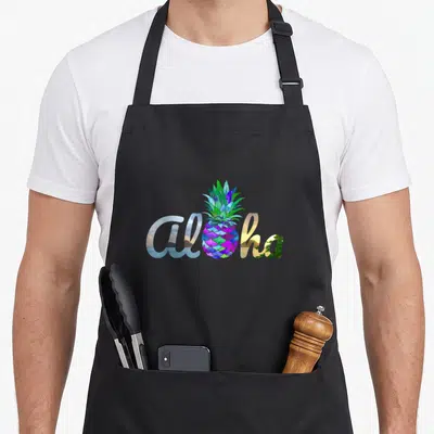 Hawaii pineapple apron - Aloha script with pineapple as letter o filled with blue purple green orange beach scene — shown on a black cotton canvas apron against a white background