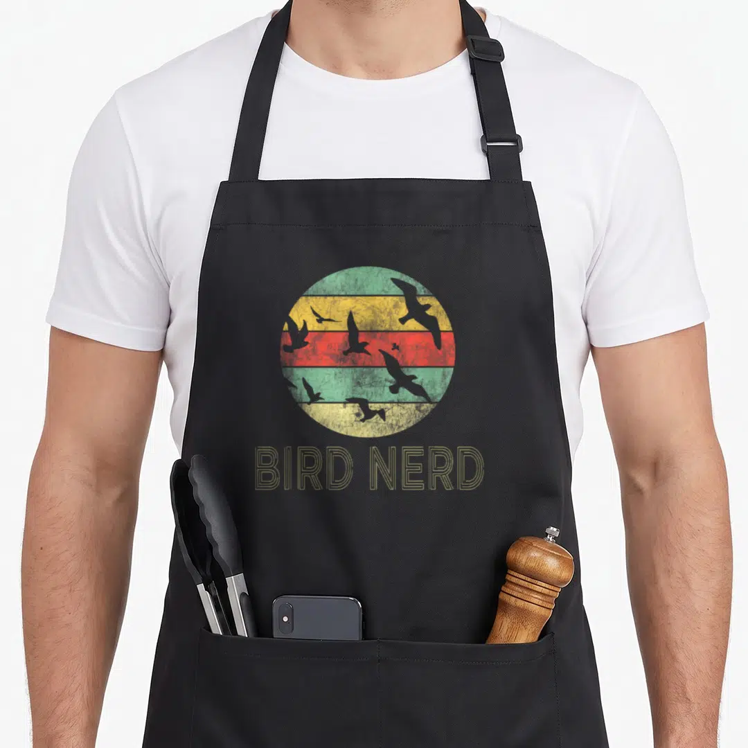 Birding watching bird apron - Retro circle with green yellow red stripes and grey bird silhouettes above outlined BIRD — shown on a black cotton canvas apron against a white background