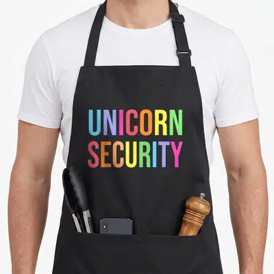 Unicorn halloween apron - Stacked rainbow text reading UNICORN SECURITY in bold block letters — shown on a black cotton canvas apron against a white background