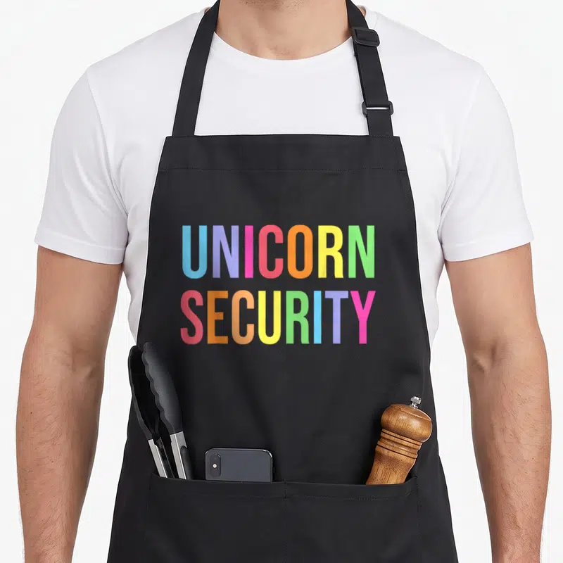Unicorn halloween apron - Stacked rainbow text reading UNICORN SECURITY in bold block letters — shown on a black cotton canvas apron against a white background