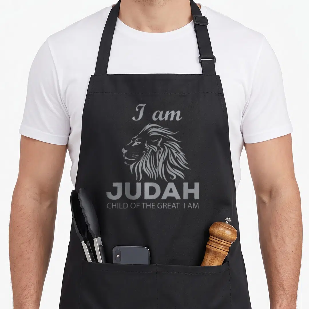 Israelite lions apron - White lion head profile between text I am JUDAH CHILD OF THE GREAT I AM — shown on a black cotton canvas apron against a white background