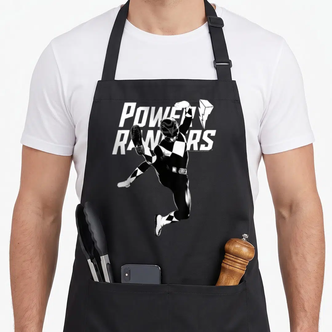 Circle rangers apron - Black and white Power Ranger jumping in front of stacked text with lightning bolt symbol — shown on a black cotton canvas apron against a white background