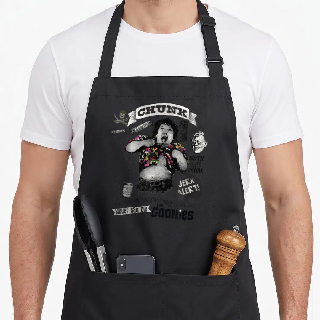 Funny chunk sloth apron - Chunk character surrounded by Goonies quotes, skull, and ice cream cup in distressed style — shown on a black cotton canvas apron against a white background