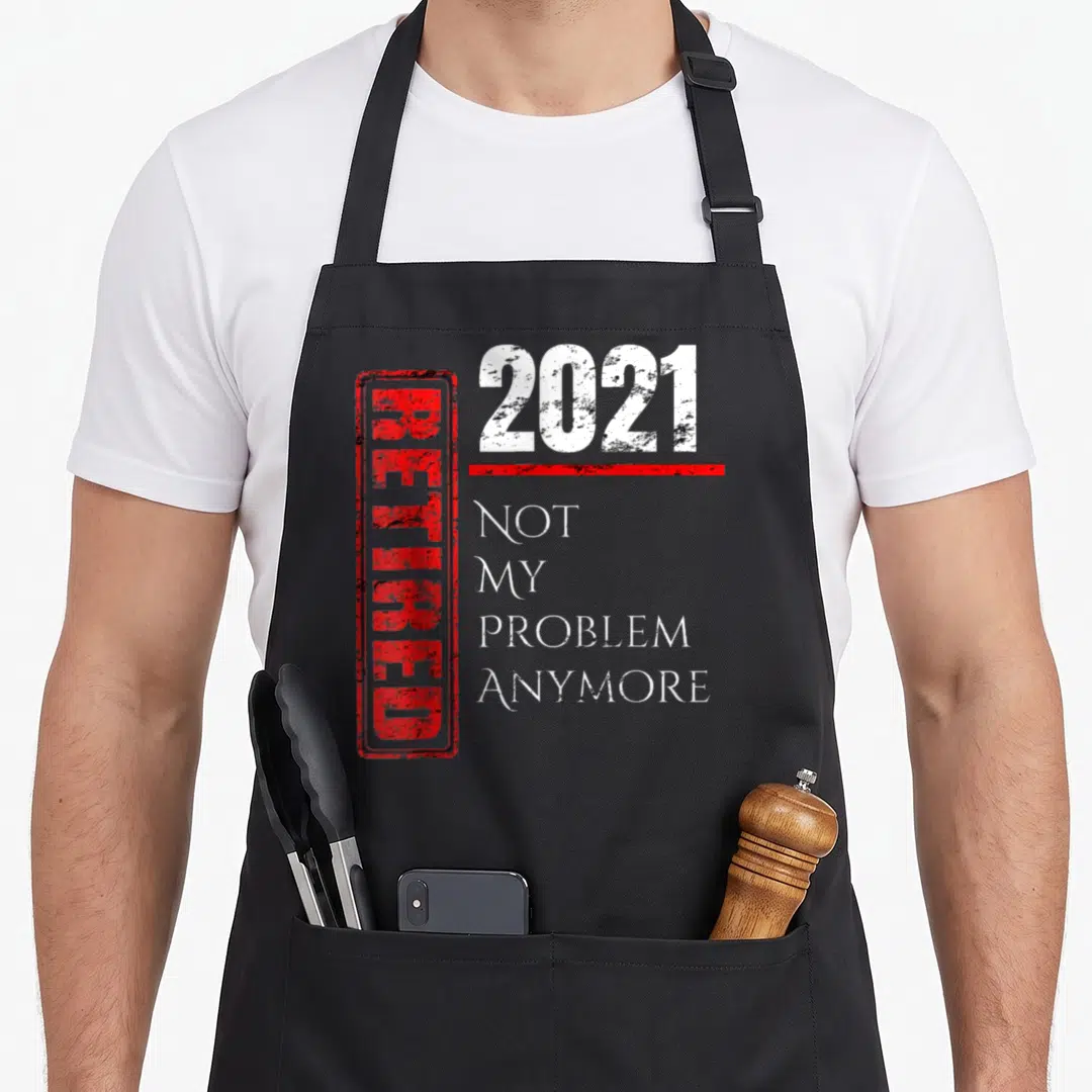 Retro anymore retirement apron - Red stamped RETIRED next to 2021 and not my problem anymore in white distressed text — shown on a black cotton canvas apron against a white background