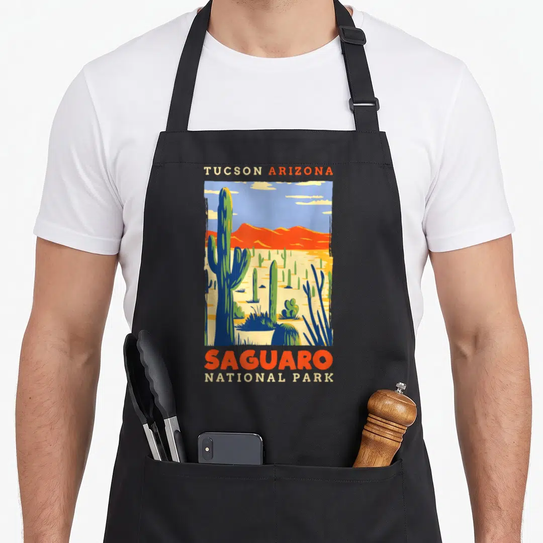 Tucson us aprons - Retro desert landscape with saguaro cactus and TUCSON ARIZONA SAGUARO NATIONAL PARK text — shown on a black cotton canvas apron against a white background