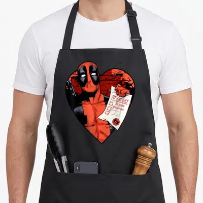 List valentine's day apron - Deadpool holding a to do list paper inside a red heart graphic — shown on a black cotton canvas apron against a white background