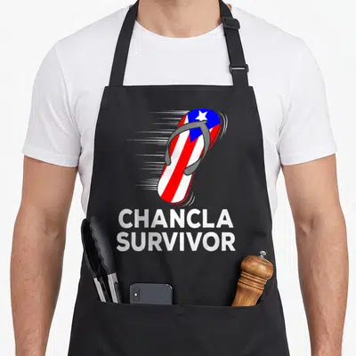 Chancla spanish aprons - Flying flip flop with flag pattern and stacked survivor text — shown on a black cotton canvas apron against a white background