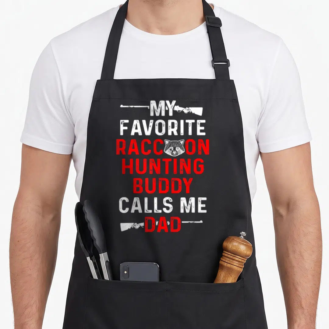 Buddy hunter apron - Stacked white and red text reading My Favorite Raccoon Hunting Buddy Calls Me Dad with a raccoon — shown on a black cotton canvas apron against a white background