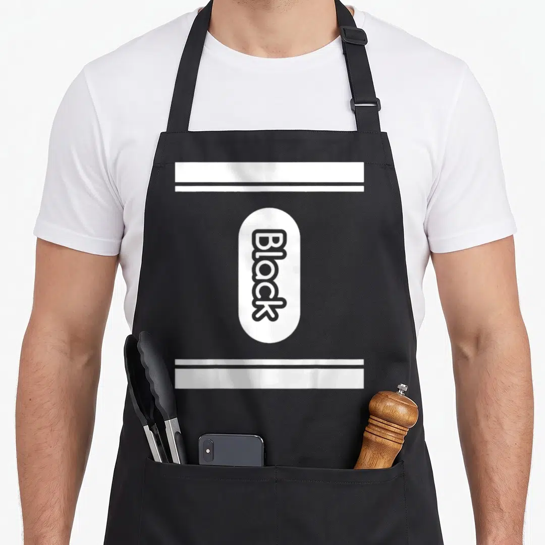 Crayon halloween friends cooking apron - Vertical Black text in white oval between two horizontal white bars on grey — shown on a black cotton canvas apron against a white background