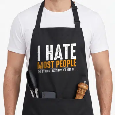Most people sarcasm apron - Distressed white and orange text reading I HATE MOST PEOPLE THE OTHERS I JUST HAVEN'T MET — shown on a black cotton canvas apron against a white background