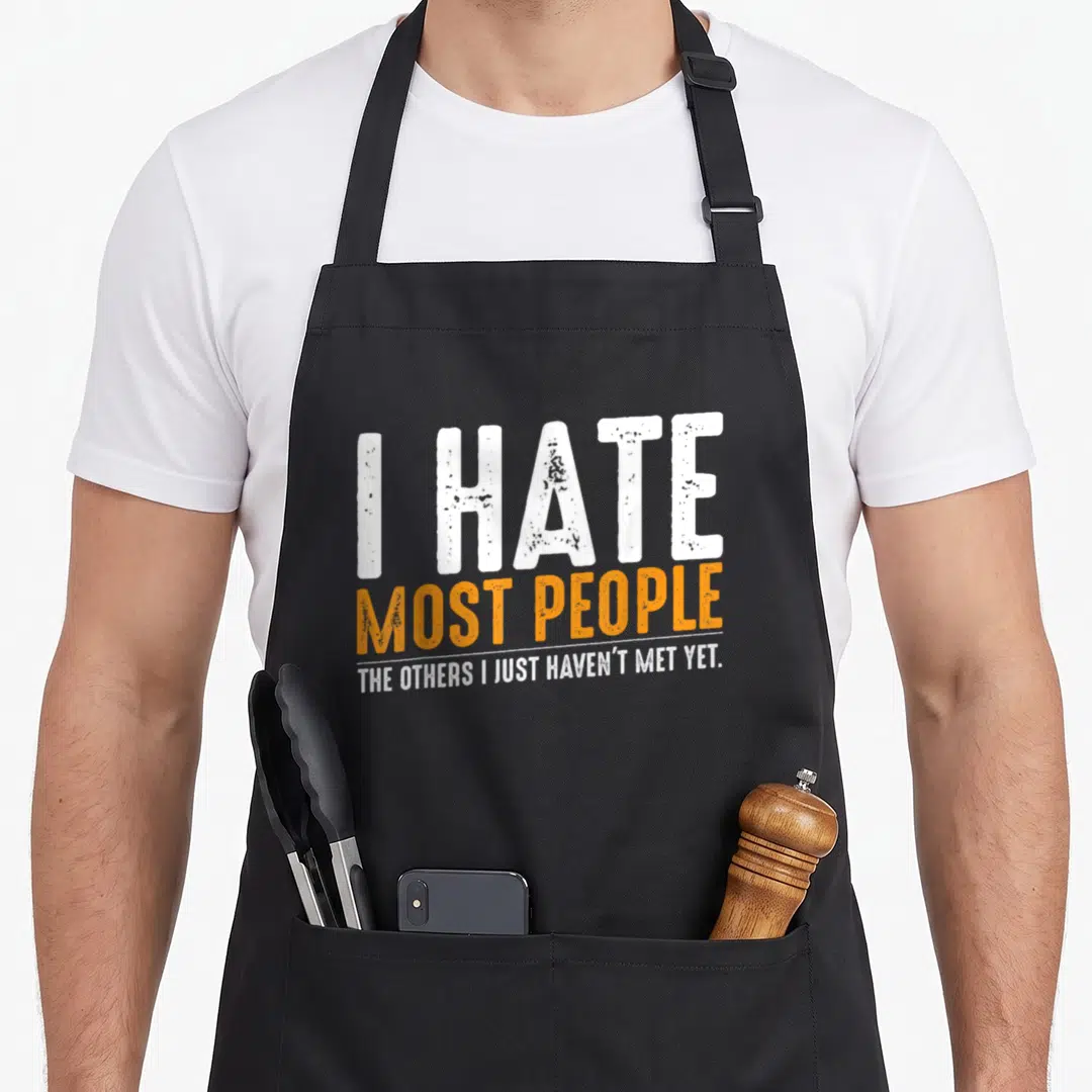 Most people sarcasm apron - Distressed white and orange text reading I HATE MOST PEOPLE THE OTHERS I JUST HAVEN'T MET — shown on a black cotton canvas apron against a white background