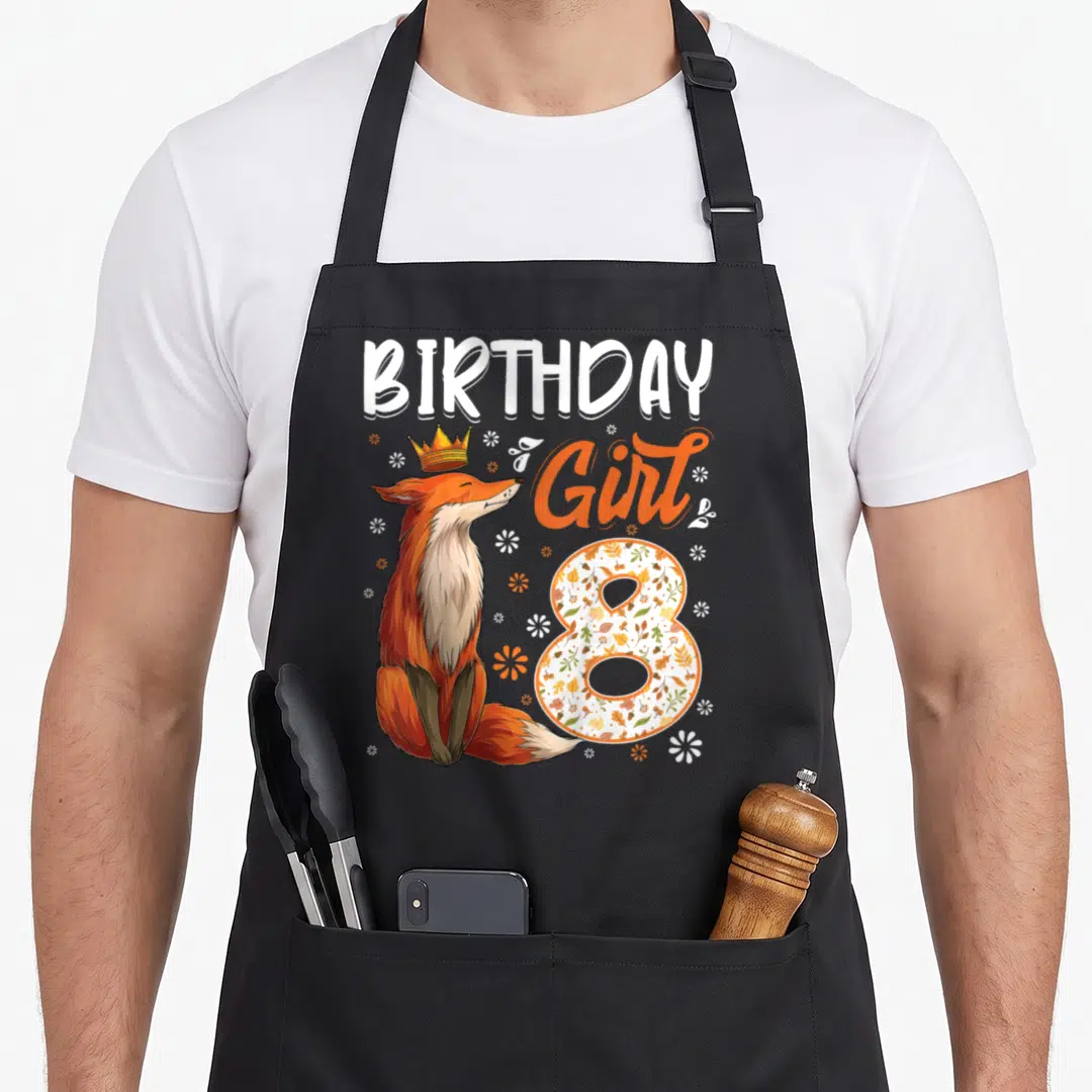 8th fox aprons - Crowned fox sitting next to BIRTHDAY Girl 8 text with floral number 8 and scattered flowers — shown on a black cotton canvas apron against a white background
