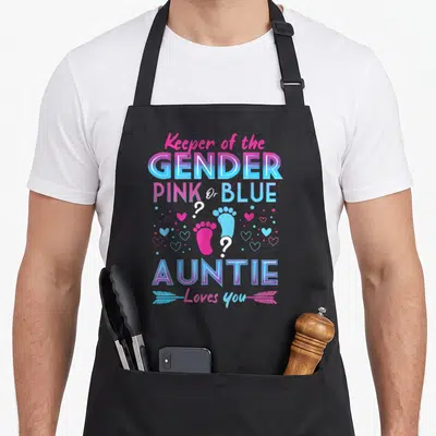 Gender blue apron or apron - Stacked pink and blue text with two baby footprints and hearts reading Keeper — shown on a black cotton canvas apron against a white background