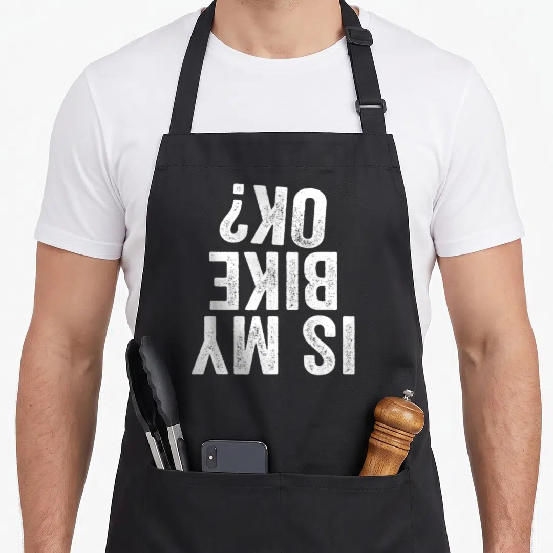 Motorcycle bike apron - White rotated text reading IS MY BIKE OK? on dark background — shown on a black cotton canvas apron against a white background